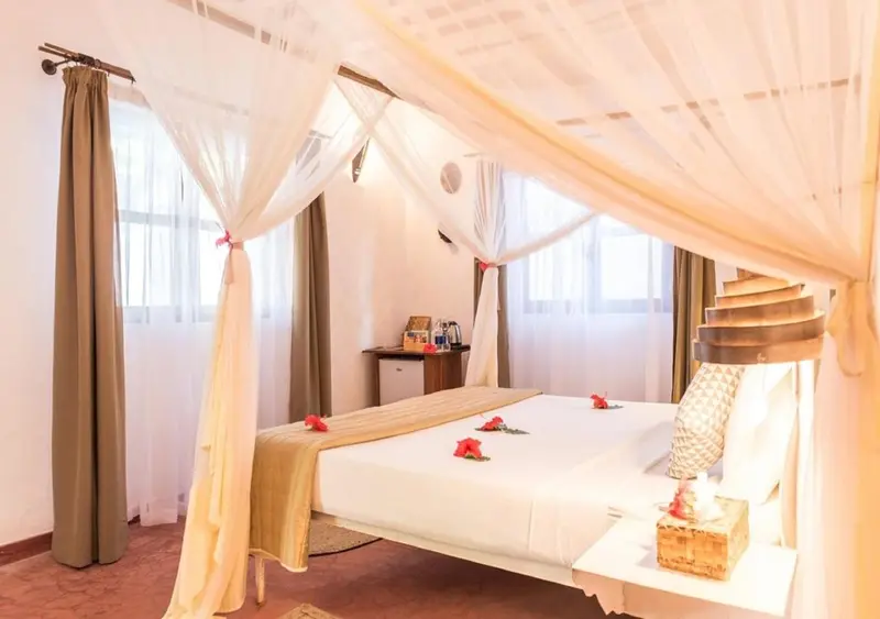 Une chambre lumineuse avec un lit à baldaquin décoré de moustiquaire et de fleurs.