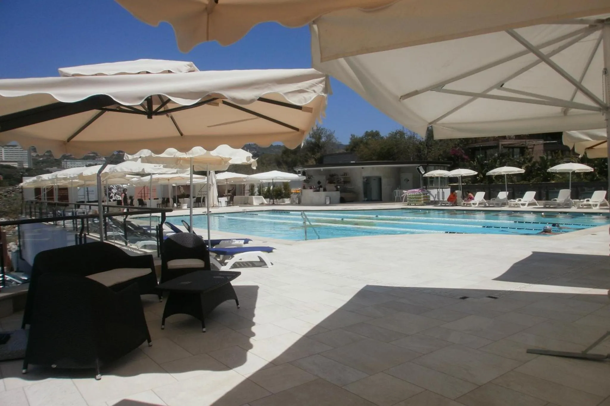 Terrasse ombragée donnant sur une piscine ensoleillée.