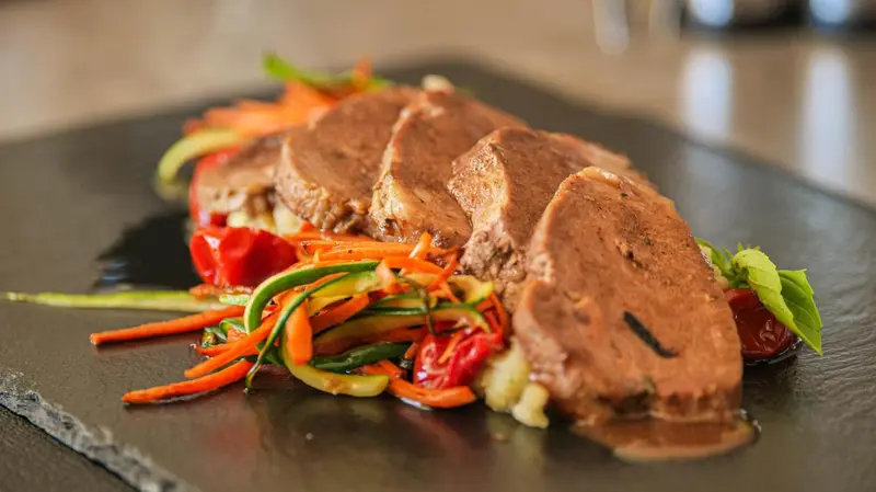 Assiette de viande froide accompagnée de légumes et d'une sauce.