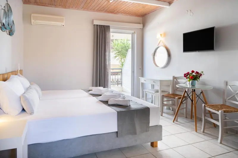 Une chambre lumineuse avec un lit double et une petite table à manger près d'une porte-fenêtre.