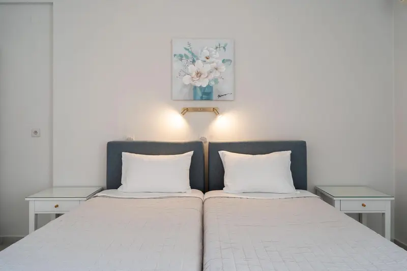 Une chambre avec deux lits simples et une décoration florale au mur.