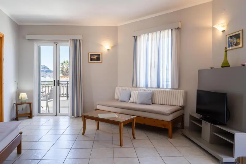 Espace de séjour lumineux avec canapé et accès à un balcon.