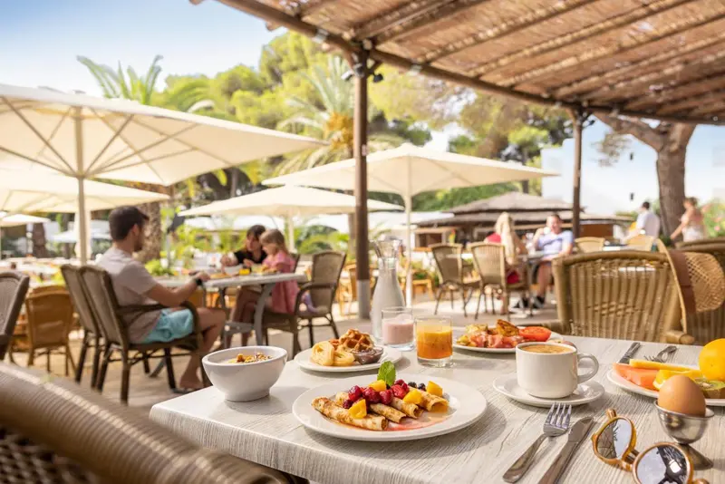 Une table est dressée avec un petit-déjeuner copieux en extérieur.