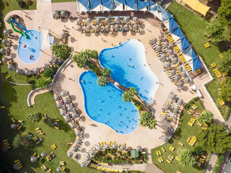 Vue aérienne d'un complexe hôtelier avec des piscines et des transats.
