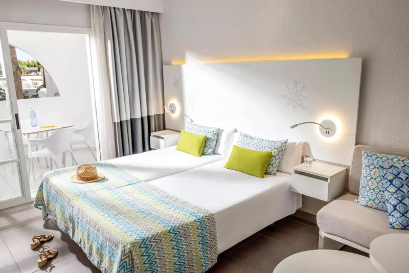 Une chambre lumineuse avec un lit double et un coin salon.