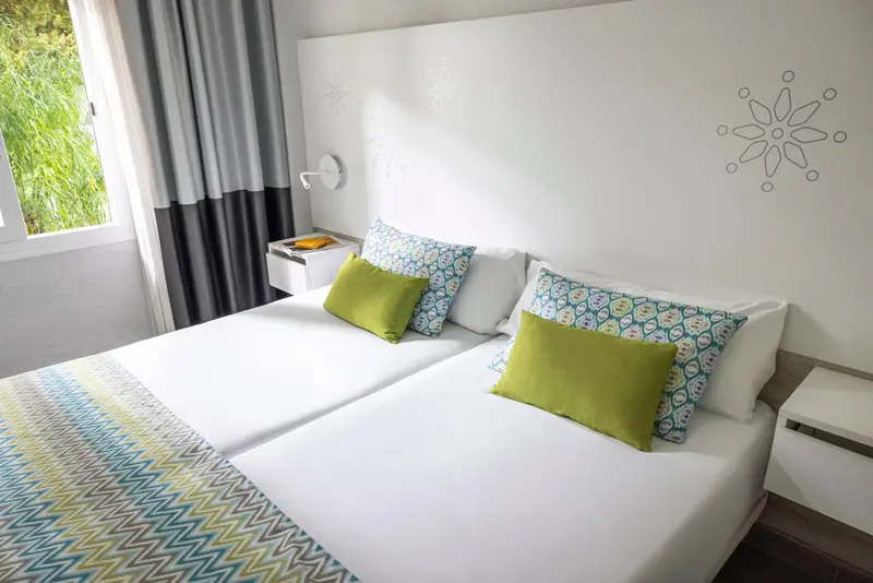 Lit double avec oreillers et couvertures blanches dans une chambre lumineuse.