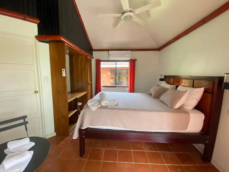 Une chambre lumineuse avec un grand lit et un bureau en bois.