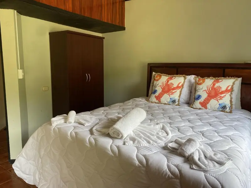 Un lit recouvert d'une courtepointe blanche et de coussins décorés, dans une chambre lumineuse.