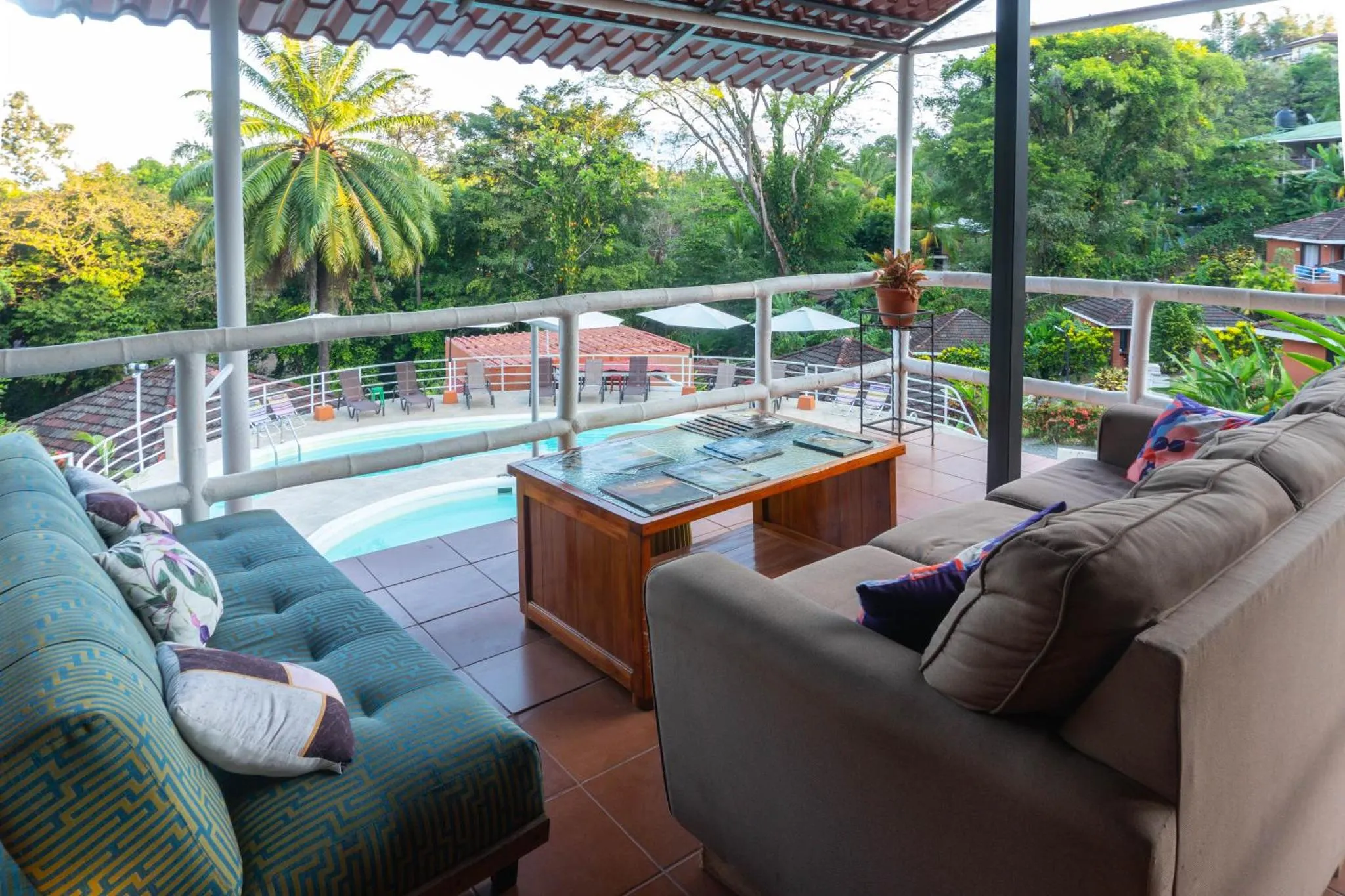 Espace de détente extérieur avec canapés et vue sur une piscine et la végétation.