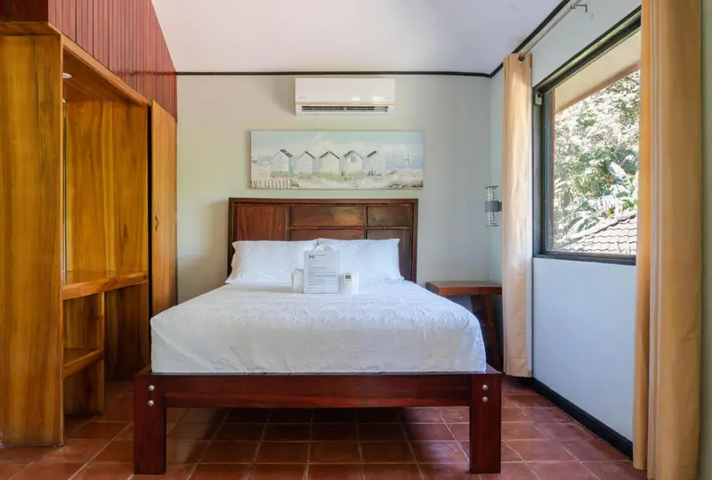 Une chambre lumineuse avec un lit double et un meuble en bois.