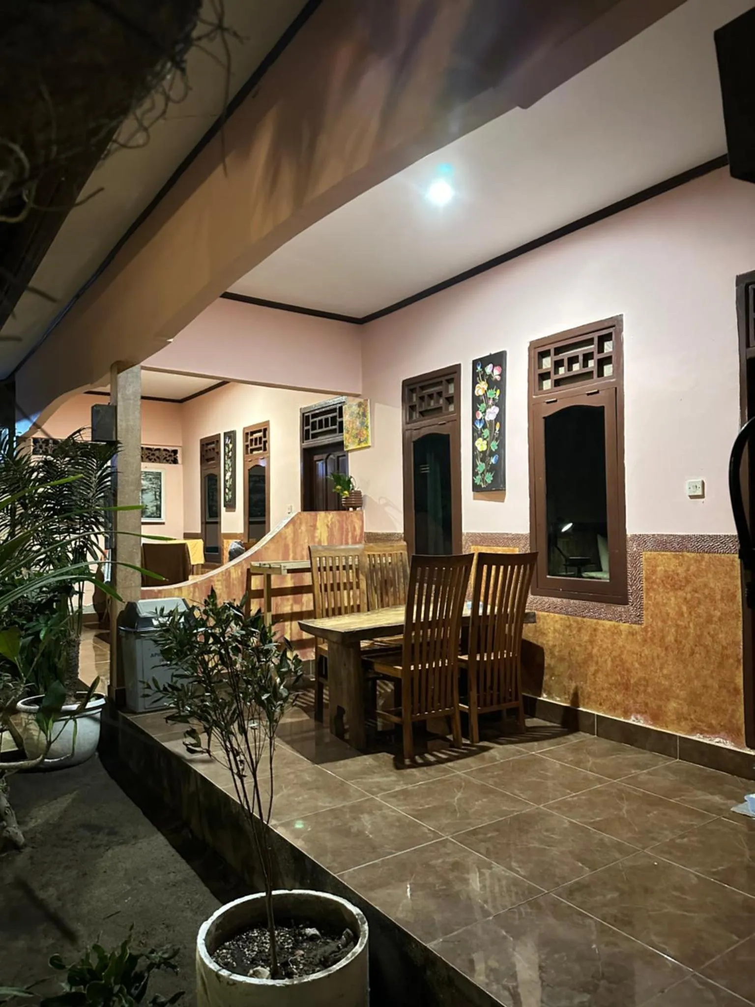 Terrasse ombragée avec tables et chaises en bois.