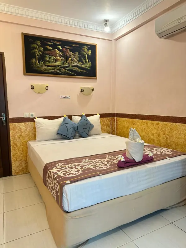 Une chambre avec un grand lit décoré de coussins et d'une composition florale.