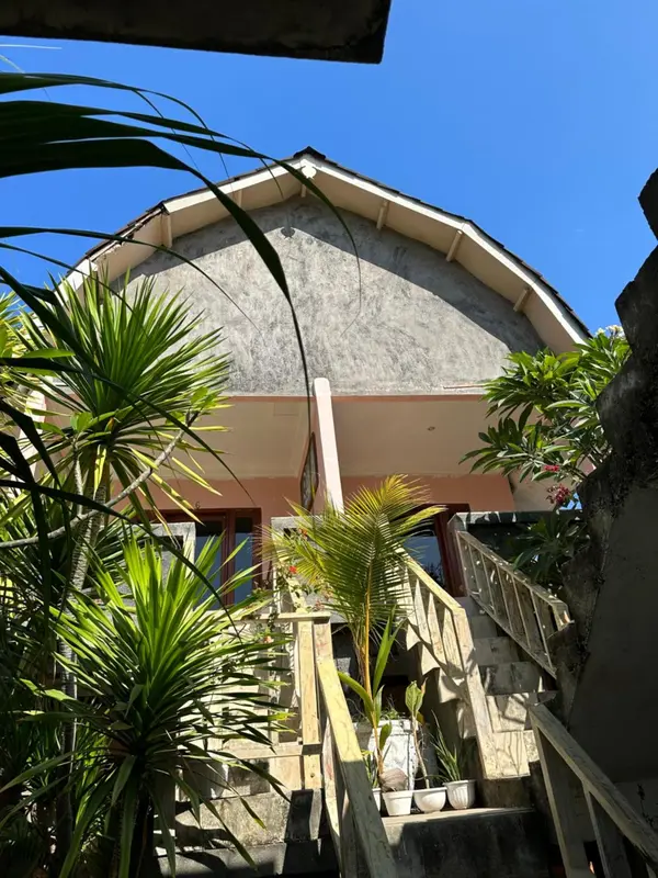 Facade d'un bâtiment avec un escalier en pierre et une végétation tropicale.
