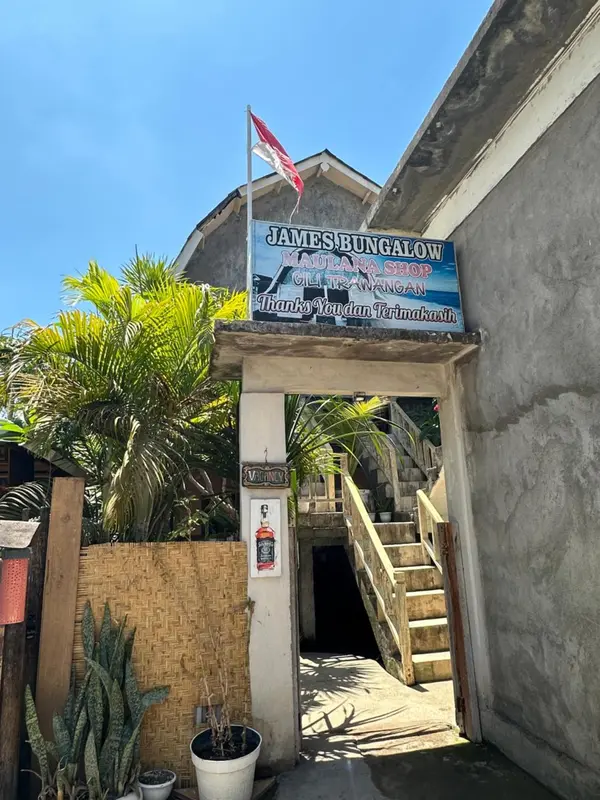 Entree d'un bungalow avec vegetation tropicale et panneaux colorés.