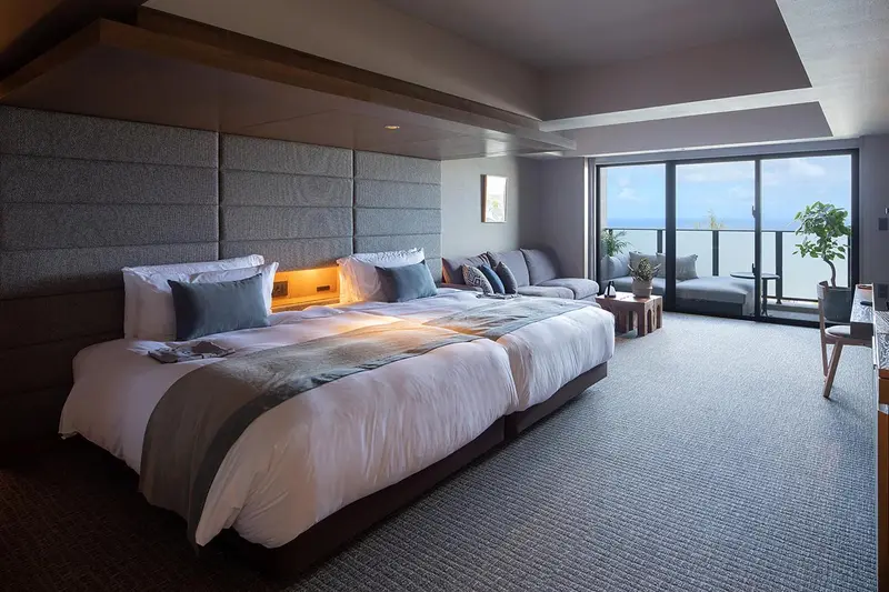 Une chambre spacieuse avec un grand lit et un coin salon lumineux.