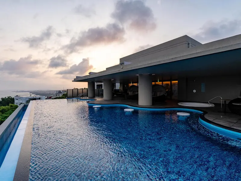 Une piscine à débordement offre une vue sur le paysage environnant au coucher du soleil.