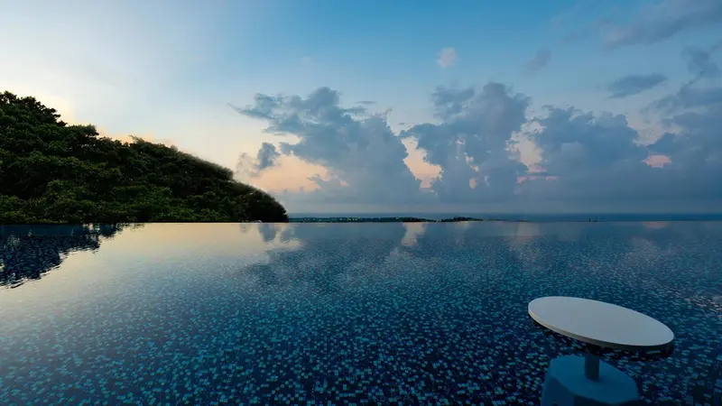 Piscine à débordement avec vue sur la mer et le ciel nuageux.