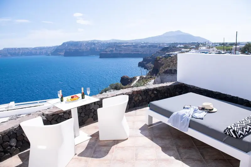 Terrasse avec mobilier blanc et vue sur la mer et les montagnes.