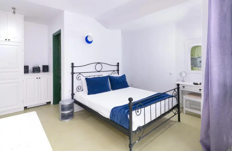 Une chambre lumineuse avec un lit double et des meubles blancs.