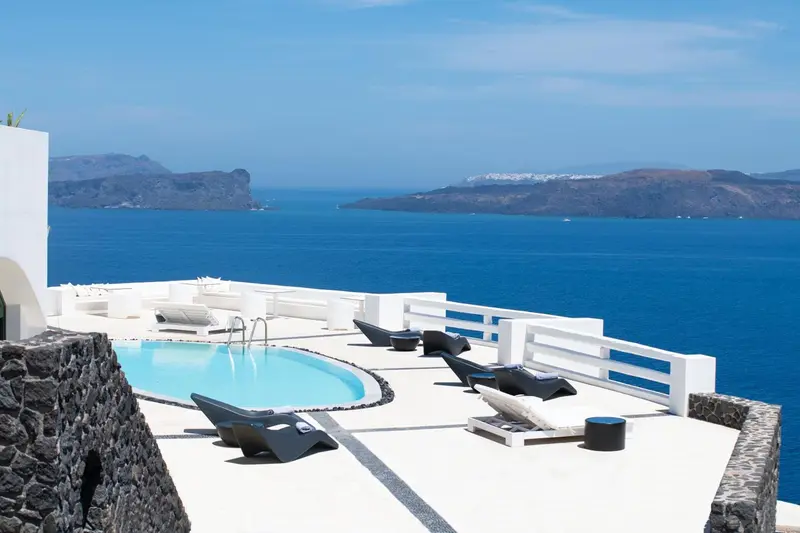 Terrasse avec piscine et chaises longues face à la mer.