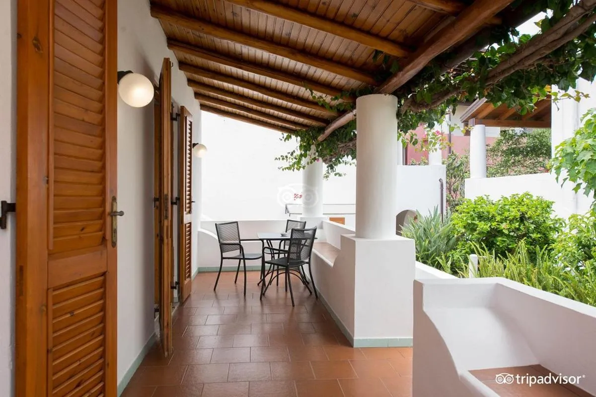 Terrasse ombragée avec table et chaises devant des portes en bois.