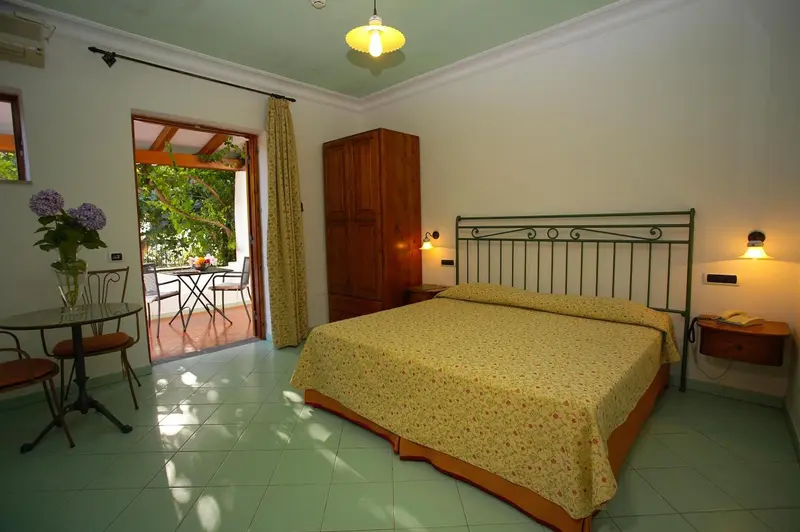 Une chambre lumineuse avec un lit et un coin repas donnant sur une terrasse.