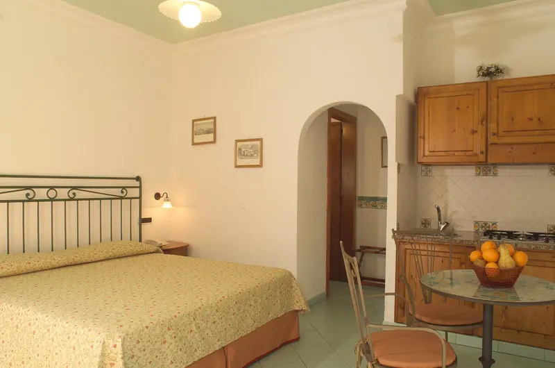 Une chambre lumineuse avec un lit et un coin cuisine.