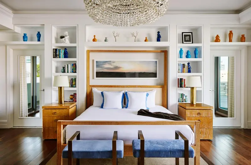 Une chambre lumineuse avec un grand lit et des bibliotheques encastrées.