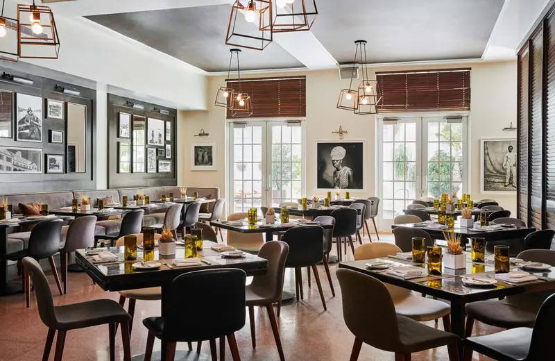 Une salle de restaurant lumineuse avec des tables dressées et des suspensions décoratives.
