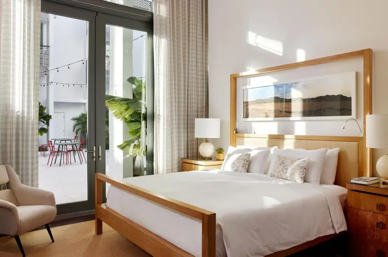 Une chambre lumineuse avec un grand lit et une vue sur une cour intérieure.