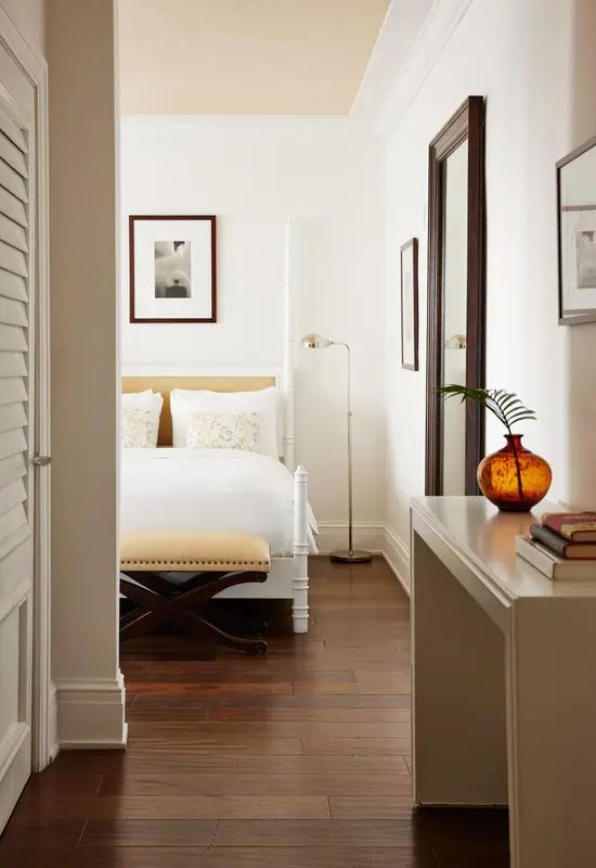 Une chambre lumineuse avec un lit à baldaquin et un parquet en bois sombre.