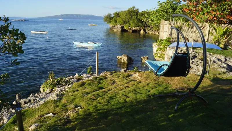 Vue sur la mer depuis un jardin avec une balancelle.