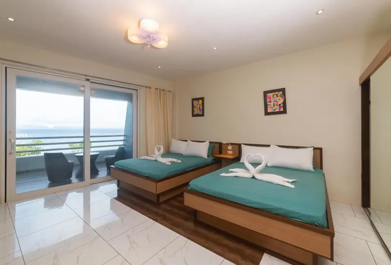 Chambre lumineuse avec deux lits et vue sur la mer.