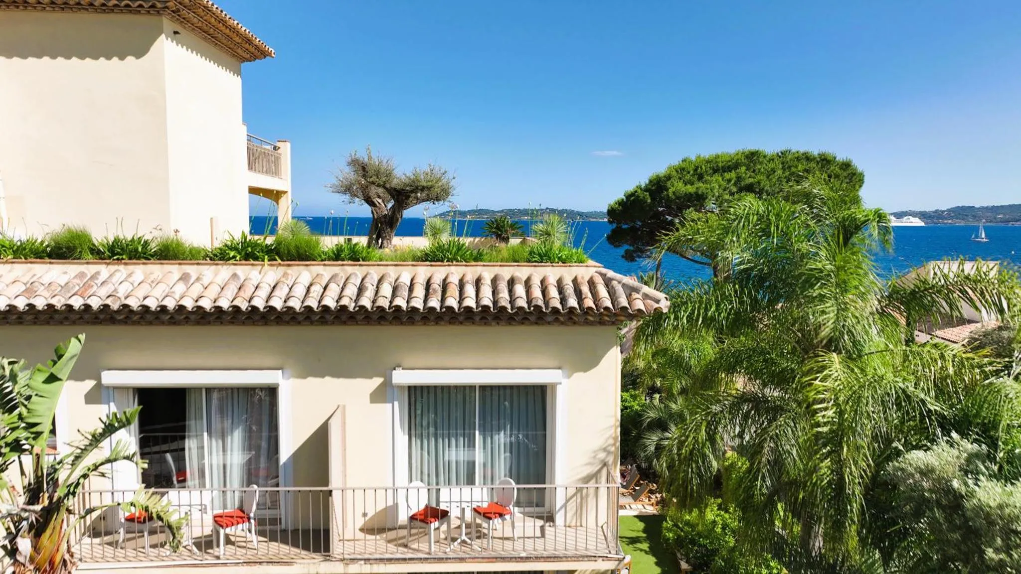 Terrasse ombragée donnant sur la mer et la végétation luxuriante.