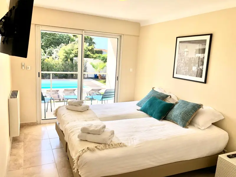 Une chambre lumineuse avec un grand lit et un accès à une piscine.