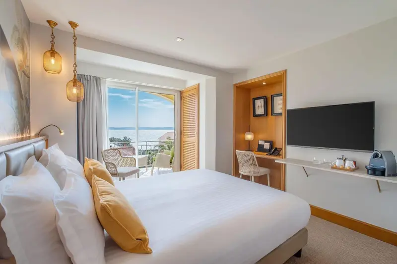 Une chambre lumineuse avec un grand lit et une vue sur la mer.
