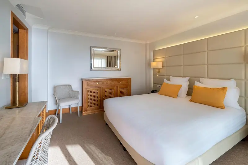 Chambre lumineuse avec un grand lit et un bureau.