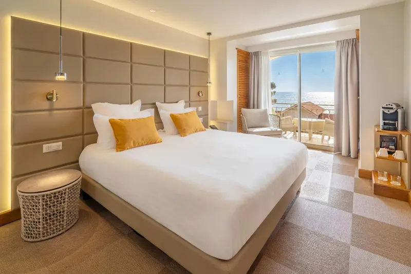 Chambre lumineuse avec un grand lit et une vue sur la mer.