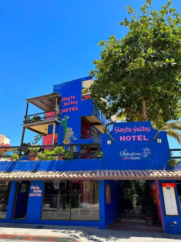 Bâtiment bleu vif avec des balcons et une végétation luxuriante.