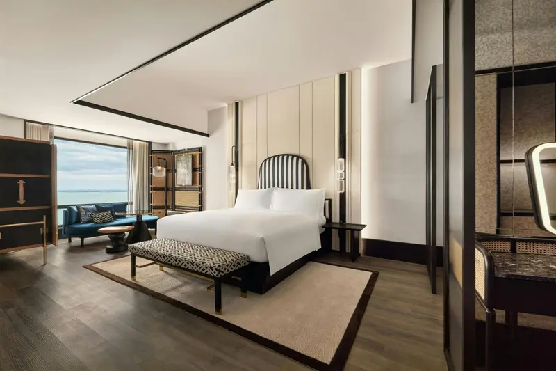 Une chambre lumineuse avec un grand lit et un coin salon donnant sur la mer.