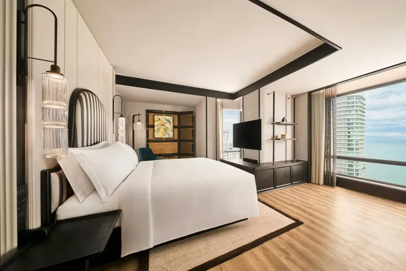 Une chambre lumineuse avec un grand lit et une vue sur la ville.