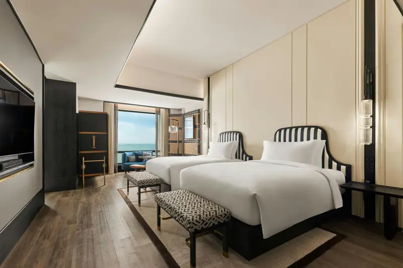 Chambre lumineuse avec deux lits et vue sur la mer.