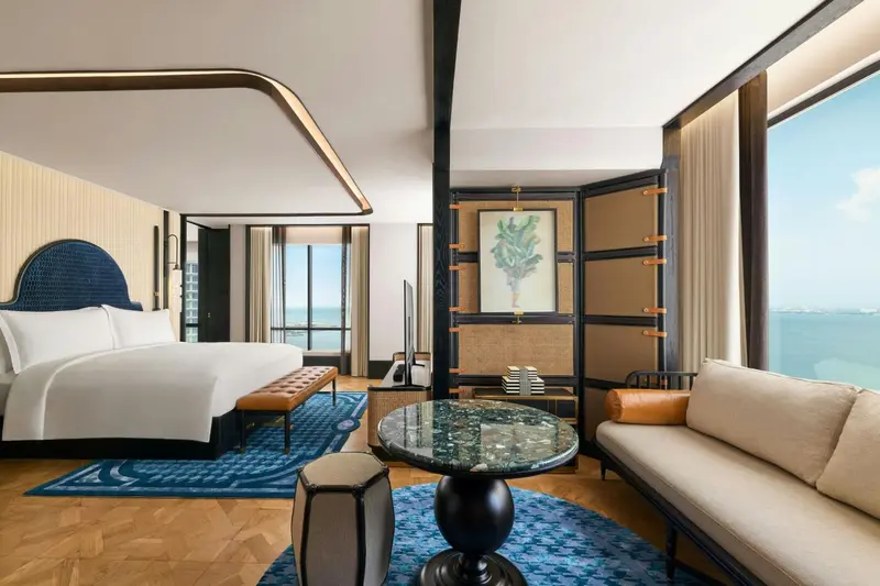 Une chambre lumineuse avec un grand lit et un espace salon.