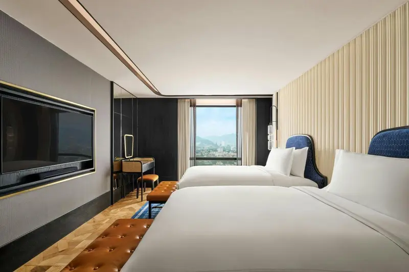 Chambre moderne avec deux lits simples et vue sur la ville.