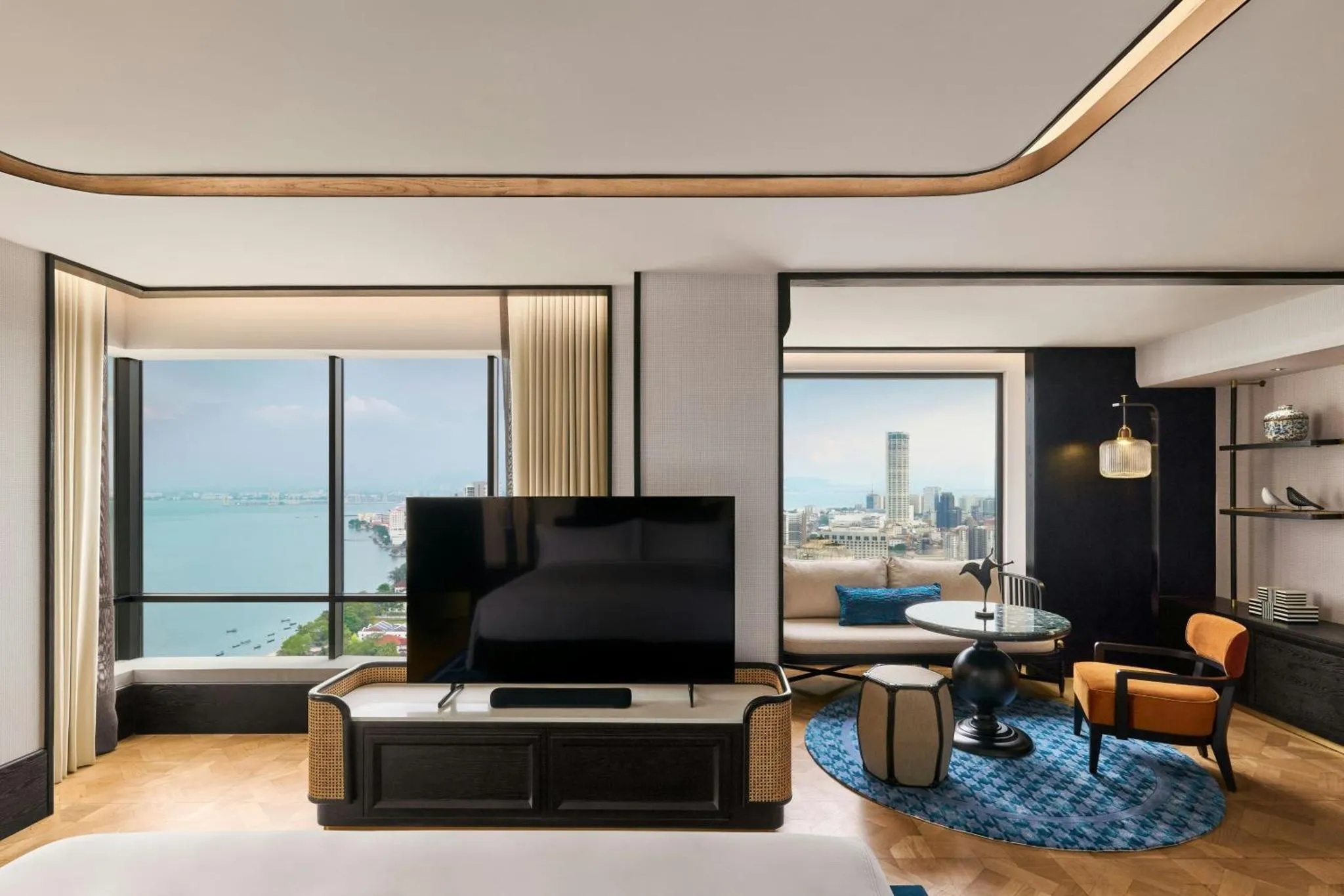 Un salon moderne avec canapé, fauteuil et vue sur la mer par de grandes fenêtres.
