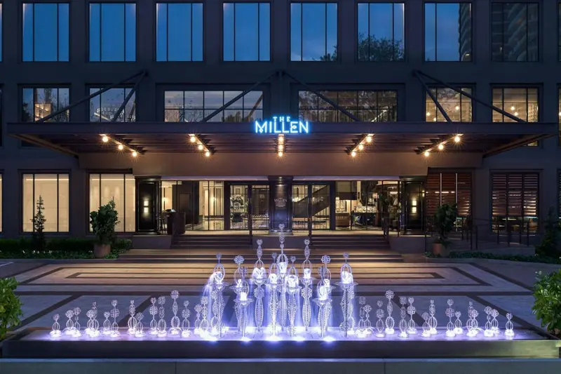 Façade d'un bâtiment moderne avec une fontaine illuminée en contrebas.
