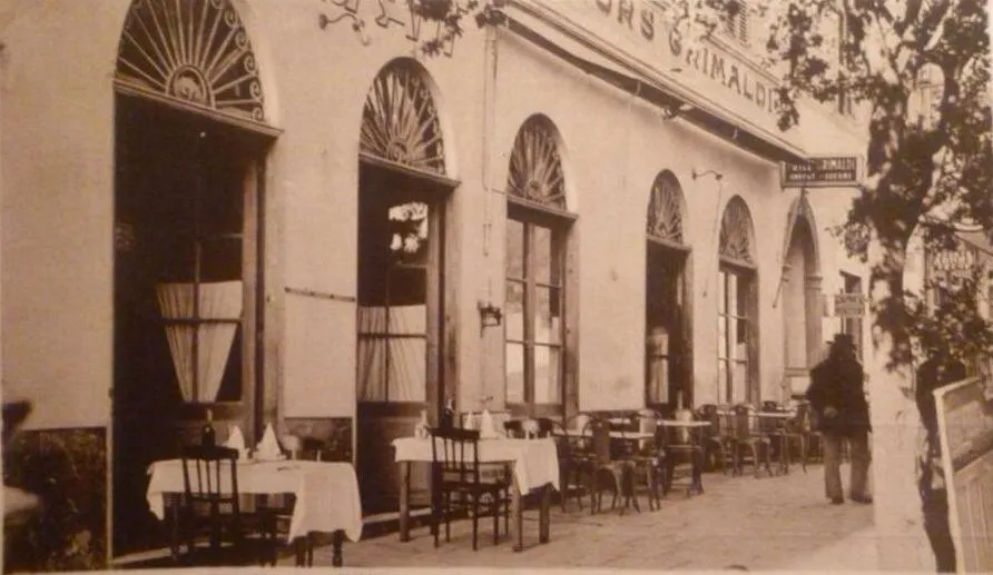 Terrasse de restaurant avec tables nappées et chaises en fer forgé.