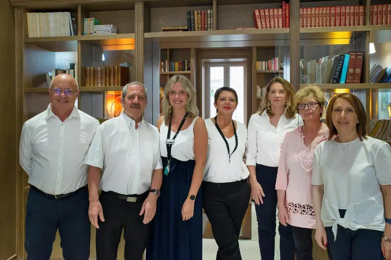 Groupe de personnes souriantes posant devant une bibliothèque.