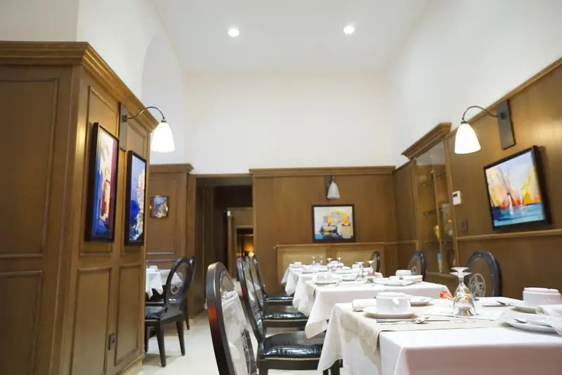 Une salle lumineuse avec des tables dressées pour un repas.