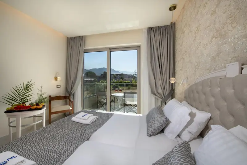 Chambre lumineuse avec un grand lit et vue sur un paysage verdoyant.